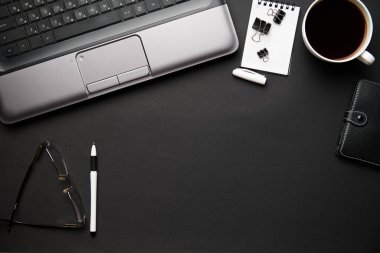 Laptop, defter, kalem ve bir sürü şeyle modern siyah ofis masasının en üst görüntüsü. Düz masa yerleşimi. Metin için alanı kopyala.