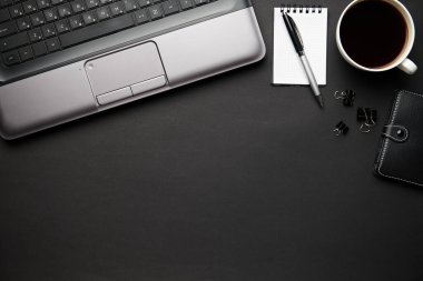 Laptop, defter, kalem ve bir sürü şeyle modern siyah ofis masasının en üst görüntüsü. Düz masa yerleşimi. Metin için alanı kopyala.