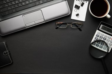 Laptop, defter, kalem ve bir sürü şeyle modern siyah ofis masasının en üst görüntüsü. Düz masa yerleşimi. Metin için alanı kopyala.