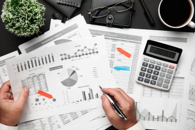 Finansal raporlarla çalışan işadamlarının üst düzey görüşü. Defteri, kalemi ve bir sürü şeyi olan modern siyah ofis masası. Düz masa düzeni.