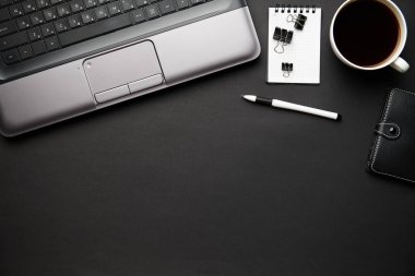 Laptop, defter, kalem ve bir sürü şeyle modern siyah ofis masasının en üst görüntüsü. Düz masa yerleşimi. Metin için alanı kopyala.