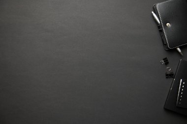 Modern siyah ofis masasının üst görüntüsü, defter, kalem ve bir sürü şey. Düz masa yerleşimi. Metin için alanı kopyala.