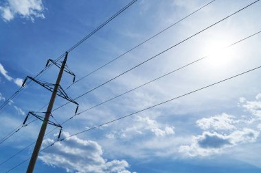 Parlak gökyüzüne karşı yüksek voltajlı elektrik hattı