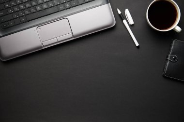 Laptop, defter, kalem ve bir sürü şeyle modern siyah ofis masasının en üst görüntüsü. Düz masa yerleşimi. Metin için alanı kopyala.