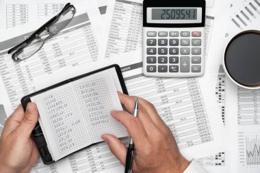 Finansal beyannamelerle çalışan iş adamlarının üst görüşü. Defteri, kalemi ve bir sürü şeyi olan modern siyah ofis masası. Düz masa düzeni.