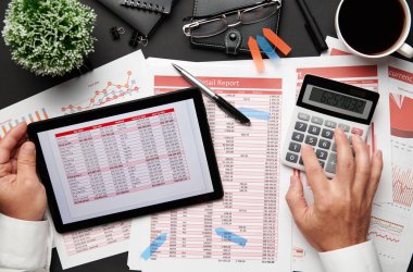 Tablet bilgisayar ve mali raporlarla çalışan işadamlarının en iyi görüşü. Defteri, kalemi ve bir sürü şeyi olan modern siyah ofis masası. Düz masa düzeni.