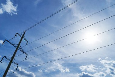 Parlak gökyüzüne karşı yüksek voltajlı elektrik hattı