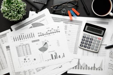 Not defteri, kalem, mali raporlar ve bir sürü şeyle modern siyah ofis masasının en üst görüntüsü. Düz masa düzeni.