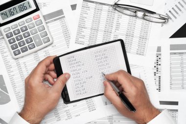 Finansal beyannamelerle çalışan iş adamlarının üst görüşü. Defteri, kalemi ve bir sürü şeyi olan modern siyah ofis masası. Düz masa düzeni.