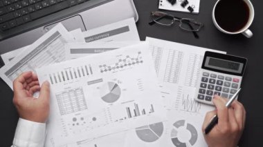 Finansal beyannamelerle çalışan iş adamlarının üst görüşü. Defteri, kalemi ve bir sürü şeyi olan modern siyah ofis masası. Düz masa düzeni.