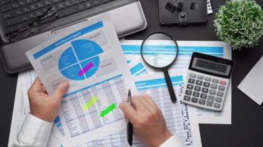 Finansal beyannamelerle çalışan iş adamlarının üst görüşü. Defteri, kalemi ve bir sürü şeyi olan modern siyah ofis masası. Düz masa düzeni.