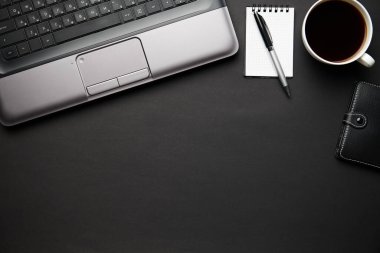 Laptop, defter, kalem ve bir sürü şeyle modern siyah ofis masasının en üst görüntüsü. Düz masa yerleşimi. Metin için alanı kopyala.
