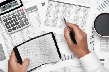 Finansal beyannamelerle çalışan iş adamlarının üst görüşü. Defteri, kalemi ve bir sürü şeyi olan modern siyah ofis masası. Düz masa düzeni.