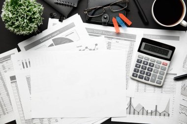 Not defteri, kalem, mali raporlar ve bir sürü şeyle modern siyah ofis masasının en üst görüntüsü. Düz masa düzeni.