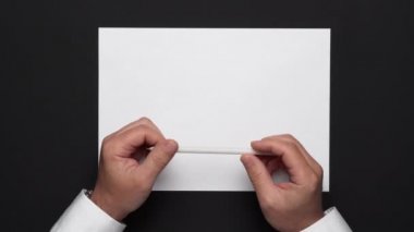 Boş bir kağıt parçası ve siyah bir masa, beyaz gömlek ve kol saati üzerinde bir iş adamının elleri.