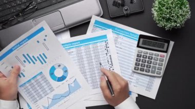 Finansal beyannamelerle çalışan iş adamlarının üst görüşü. Defteri, kalemi ve bir sürü şeyi olan modern siyah ofis masası. Düz masa düzeni.