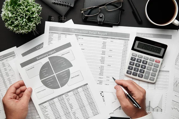 Finansal raporlarla çalışan işadamlarının üst düzey görüşü. Defteri, kalemi ve bir sürü şeyi olan modern siyah ofis masası. Düz masa düzeni.