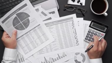 Finansal beyannamelerle çalışan iş adamlarının üst görüşü. Defteri, kalemi ve bir sürü şeyi olan modern siyah ofis masası. Düz masa düzeni. 
