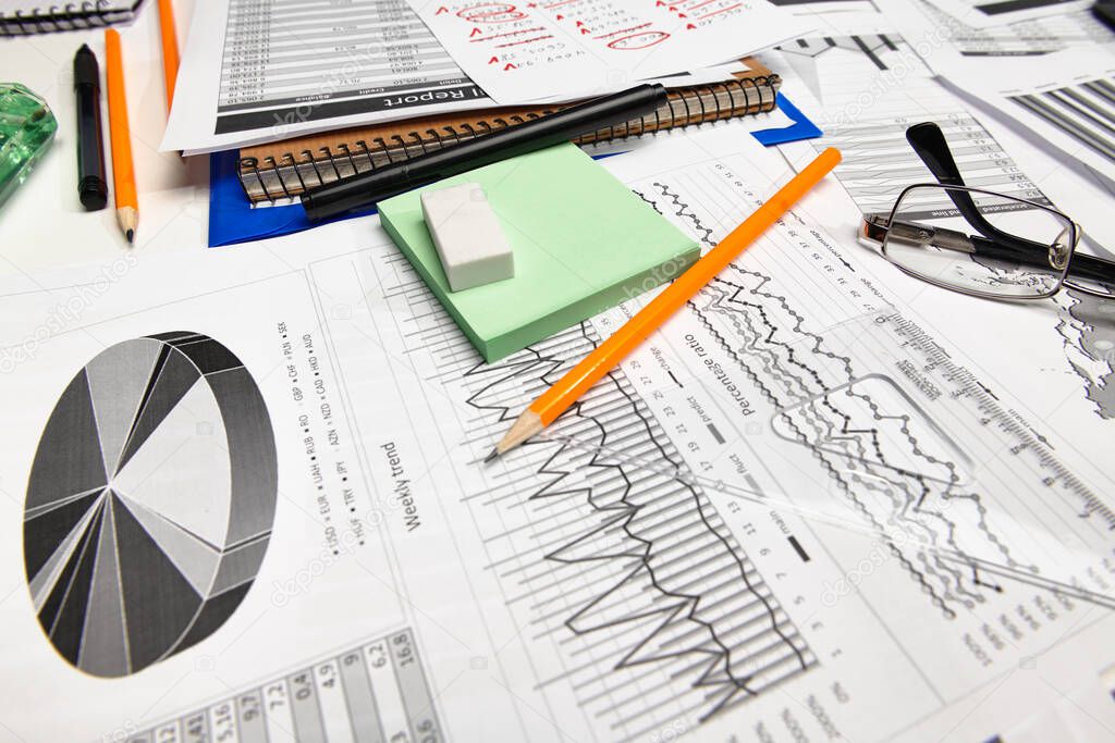 Top view of office worker's desk - work with financial reports, analysis and accounting, tables and graphs, various office items for bookkeeping