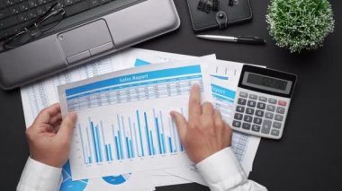Finansal beyannamelerle çalışan iş adamlarının üst görüşü. Defteri, kalemi ve bir sürü şeyi olan modern siyah ofis masası. Düz masa düzeni. 