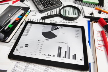 Ofis çalışanının masasının üst görünümü - tablet bilgisayar ve mali raporlar, analiz ve muhasebe, tablolar ve grafikler, muhasebe tutmak için çeşitli ofis öğeleri ile çalışma