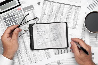Finansal beyannamelerle çalışan iş adamlarının üst görüşü. Defteri, kalemi ve bir sürü şeyi olan modern siyah ofis masası. Düz masa düzeni.