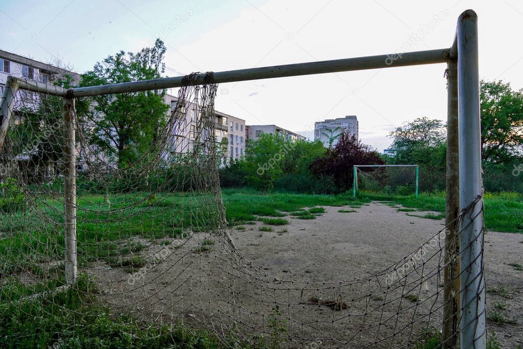 abandoned football field, goal with a torn net in a vacant lot