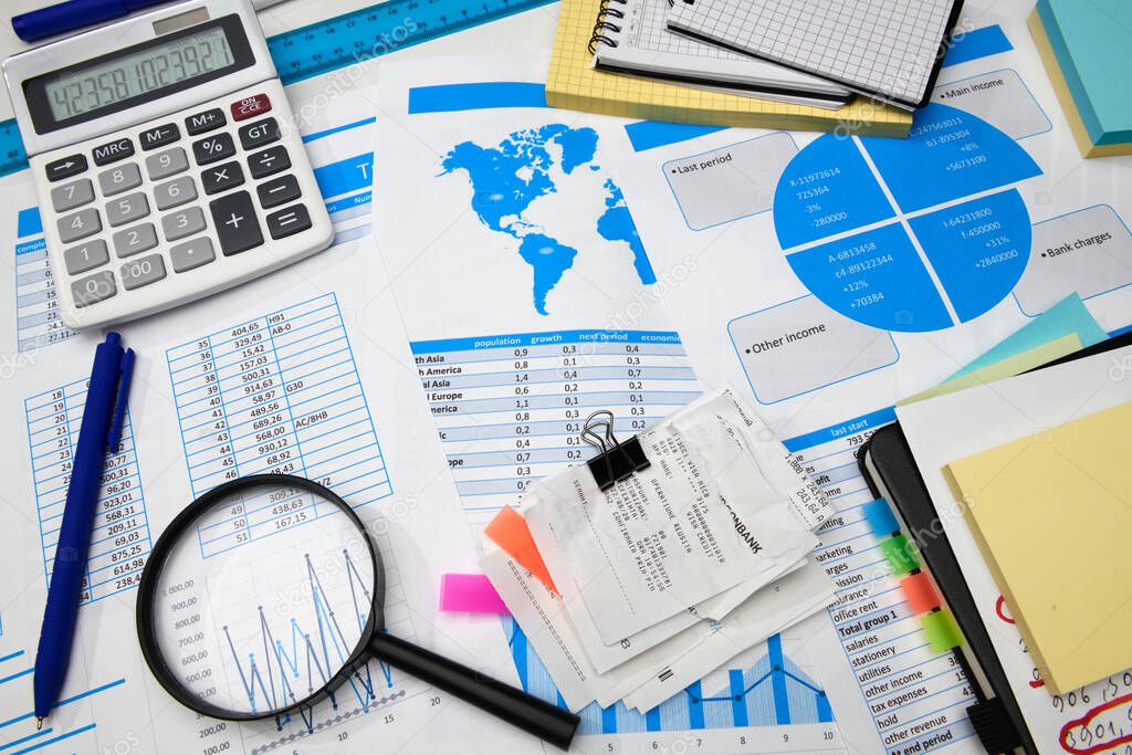 business office desk closeup - financial reports, analysis and accounting, set of documents, tables and graphs, various items for bookkeeping, calculator