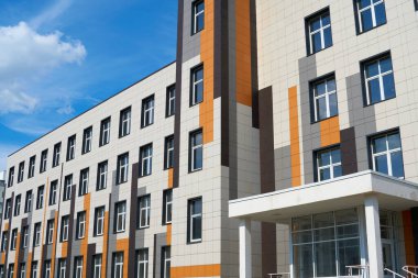 Parlak güneşli bir günde modern bir binanın ön cephesi, yan ve pencereler, yeni binanın güzel dış görünüşü.