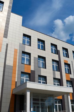 Parlak güneşli bir günde modern bir binanın ön cephesi, yan ve pencereler, yeni binanın güzel dış görünüşü.