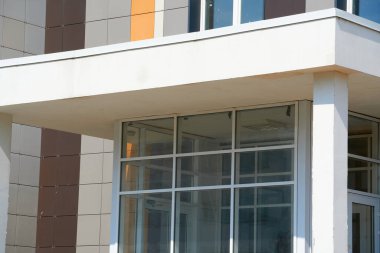 Parlak güneşli bir günde modern bir binanın ön cephesi, yan ve pencereler, yeni binanın güzel dış görünüşü.