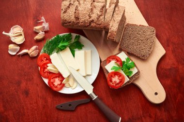 sağlıklı yiyecekler - ahşap zemin üzerinde taze ekmek ve peynir, domates, yeşillikler ve sebzeler