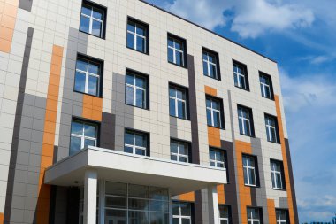 Parlak güneşli bir günde modern bir binanın ön cephesi, yan ve pencereler, yeni binanın güzel dış görünüşü.