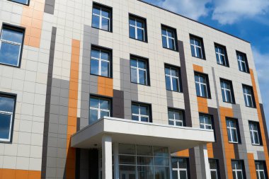 Parlak güneşli bir günde modern bir binanın ön cephesi, yan ve pencereler, yeni binanın güzel dış görünüşü.