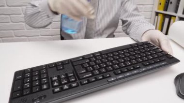 Ofis masasını temizleme ya da dezenfekte etme kavramı - bir işadamı işyerini, bilgisayar klavyesini, evrak klasörlerini, sprey tabanca dezenfektanını, eldivenleri ve kağıt peçeteleri temizler. Mikropların, virüslerin ve toprağın temiz yüzeyleri.
