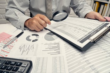 İş analizi ve muhasebe konsepti. Belge, hesap çizelgesi, hesap makinesi ve tablet bilgisayar kullanarak çalışan bir işadamı. Ofis masası kapanıyor..