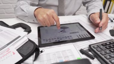 İş analizi ve muhasebe konsepti. Belge, hesap çizelgesi, hesap makinesi ve tablet bilgisayar kullanarak çalışan bir işadamı. Ofis masası kapanıyor.. 