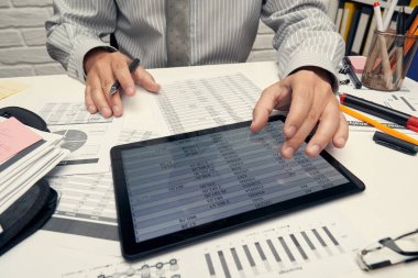 İş analizi ve muhasebe konsepti. Belge, hesap çizelgesi, hesap makinesi ve tablet bilgisayar kullanarak çalışan bir işadamı. Ofis masası kapanıyor..
