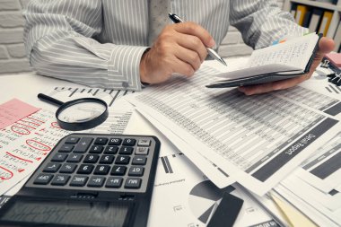 İş analizi ve muhasebe konsepti. Belge, hesap çizelgesi, hesap makinesi ve tablet bilgisayar kullanarak çalışan bir işadamı. Ofis masası kapanıyor..