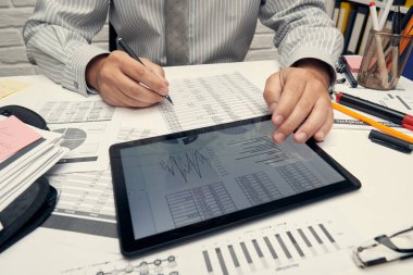 İş analizi ve muhasebe konsepti. Belge, hesap çizelgesi, hesap makinesi ve tablet bilgisayar kullanarak çalışan bir işadamı. Ofis masası kapanıyor..