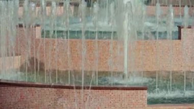 Parlak bir yaz gününde şehir çeşmesinin yakınında, su püskürtüyor.