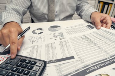 İş analizi ve muhasebe konsepti. Belge, hesap çizelgesi, hesap makinesi ve tablet bilgisayar kullanarak çalışan bir işadamı. Ofis masası kapanıyor..