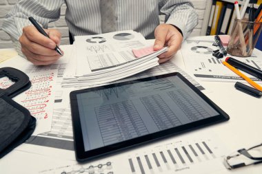 İş analizi ve muhasebe konsepti. Belge, hesap çizelgesi, hesap makinesi ve tablet bilgisayar kullanarak çalışan bir işadamı. Ofis masası kapanıyor..