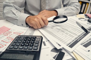 İş analizi ve muhasebe konsepti. Belge, hesap çizelgesi, hesap makinesi ve tablet bilgisayar kullanarak çalışan bir işadamı. Ofis masası kapanıyor..