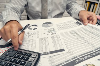 İş analizi ve muhasebe konsepti. Belge, hesap çizelgesi, hesap makinesi ve tablet bilgisayar kullanarak çalışan bir işadamı. Ofis masası kapanıyor..