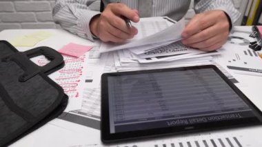 İş analizi ve muhasebe konsepti. Belge, hesap çizelgesi, hesap makinesi ve tablet bilgisayar kullanarak çalışan bir işadamı. Ofis masası kapanıyor.. 