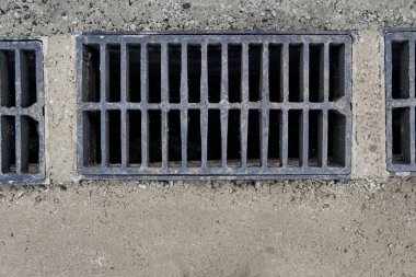 Yolda ya da kaldırımda yeni yağmur suyu ızgarası, beton döşeme. Şiddetli yağmurda suyu boşaltmak için şehir kanalizasyon sistemi
