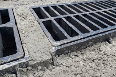 Yolda ya da kaldırımda yeni yağmur suyu ızgarası, beton döşeme. Şiddetli yağmurda suyu boşaltmak için şehir kanalizasyon sistemi