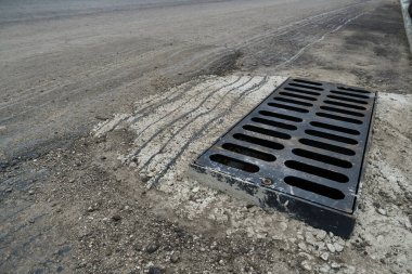 Yolda ya da kaldırımda yeni yağmur suyu ızgarası, beton döşeme. Şiddetli yağmurda suyu boşaltmak için şehir kanalizasyon sistemi