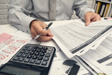 İş analizi ve muhasebe konsepti. Belge, hesap çizelgesi, hesap makinesi ve tablet bilgisayar kullanarak çalışan bir işadamı. Ofis masası kapanıyor..